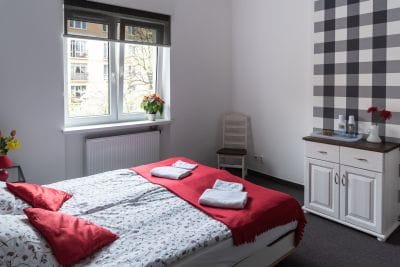 Pokój dwuosobowy na pierwszym piętrze, z szerokim 220cm/200cm, wygodnym łóżkiem, dużym ręcznikiem i dywanikiem łazienkowym pod stopy, szafką i oknem z widokiem na ogród